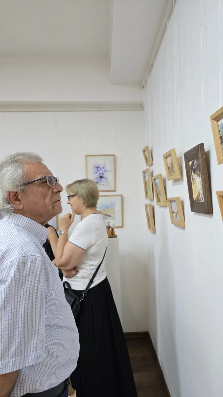 A couple leaning in to look closely at the smaller framed works